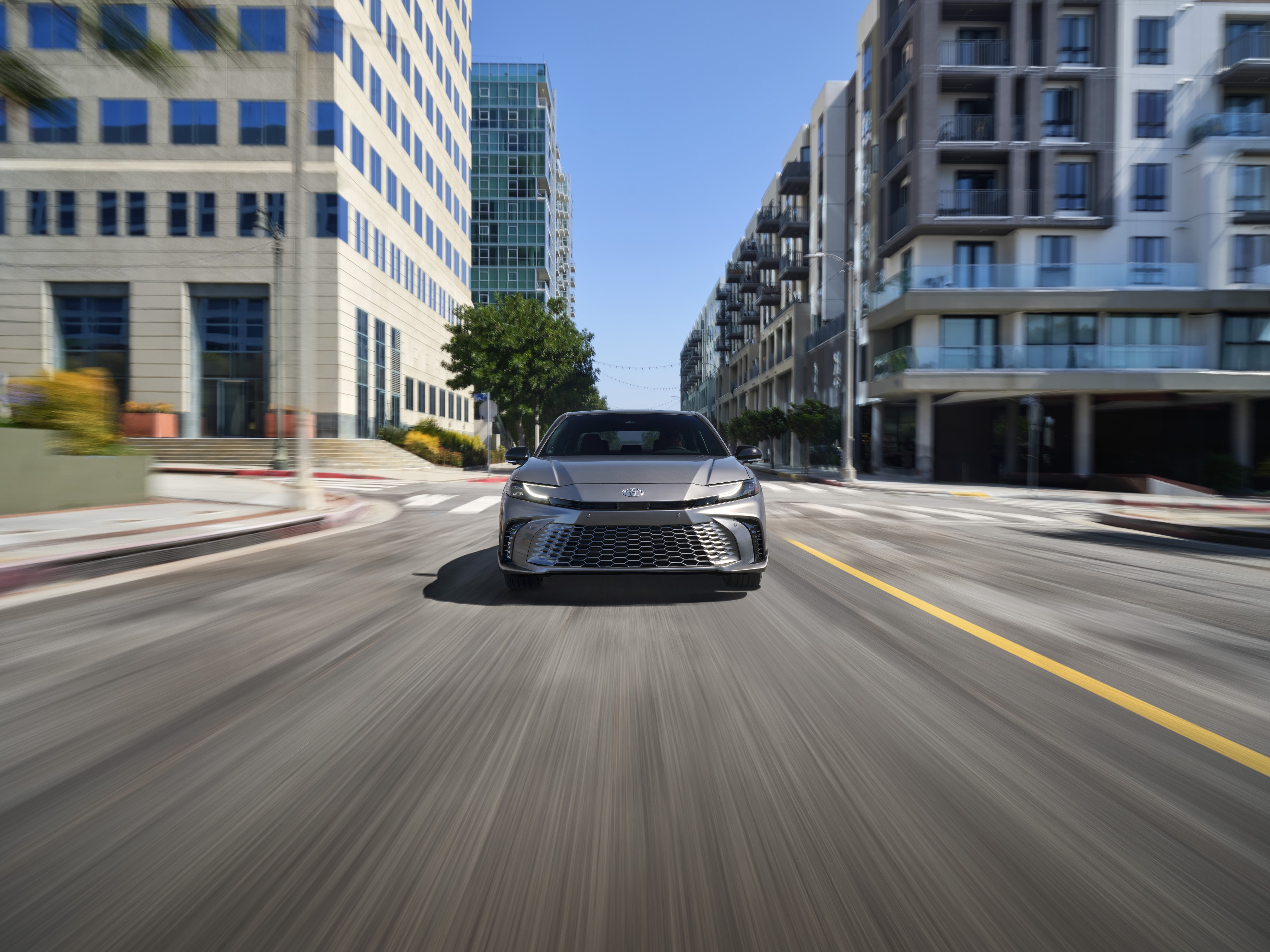 All-New 2025 Toyota Camry Revealed in Celestial Silver driving through a city in a blur