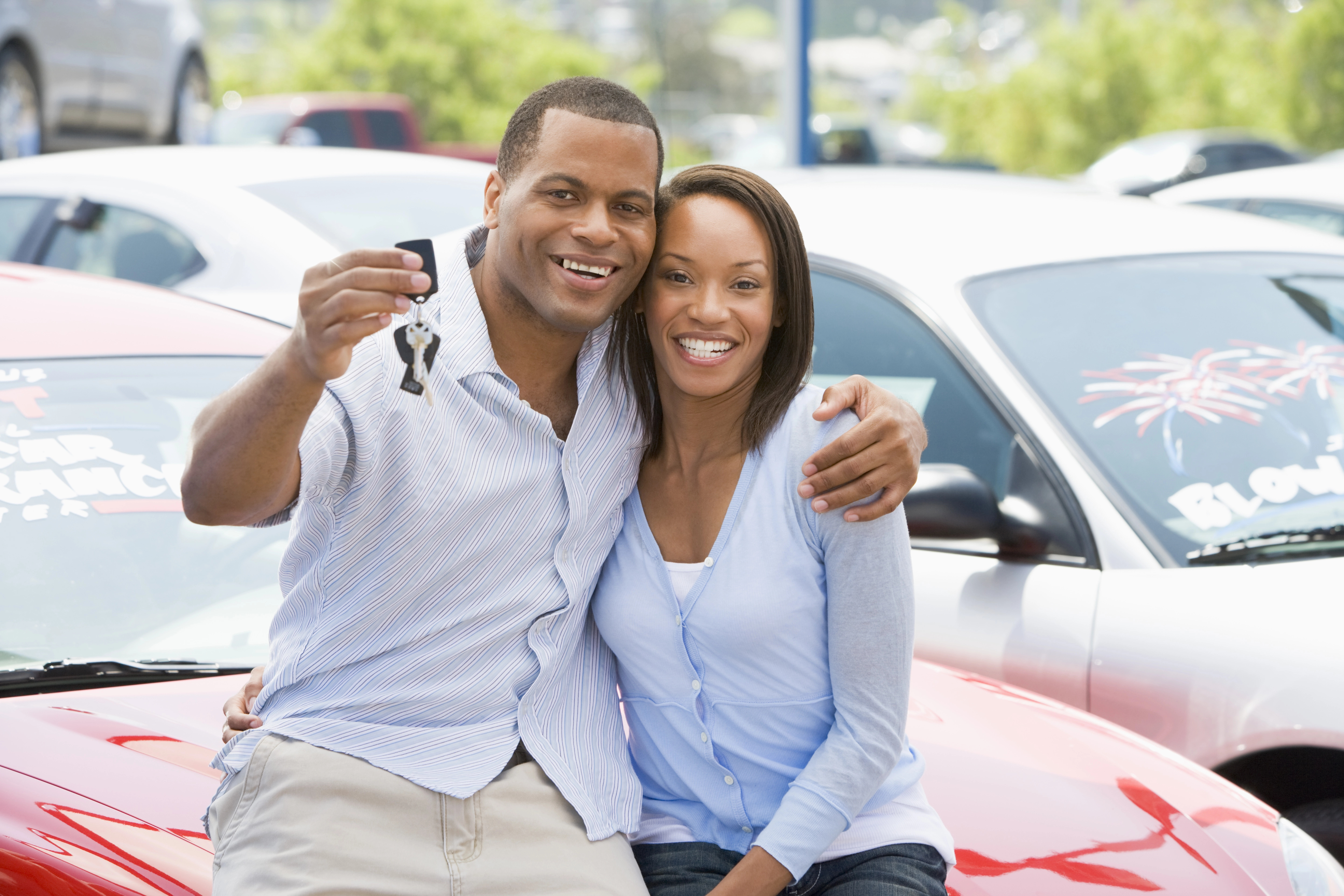 couple sitting in front of the newly purchased used vehicle holding the keys