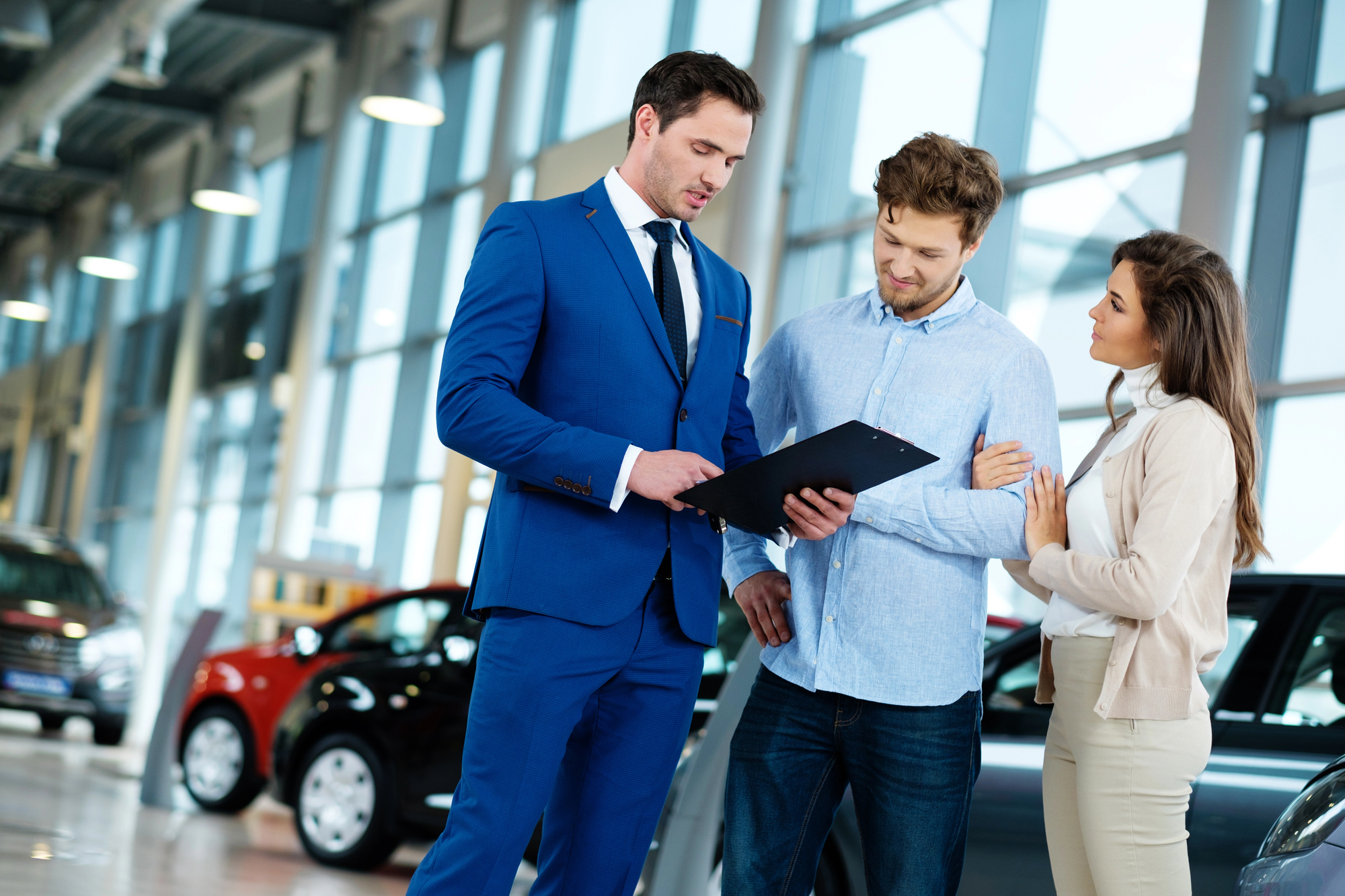 car salesmen showing facts and figures to a couple at a car dealership