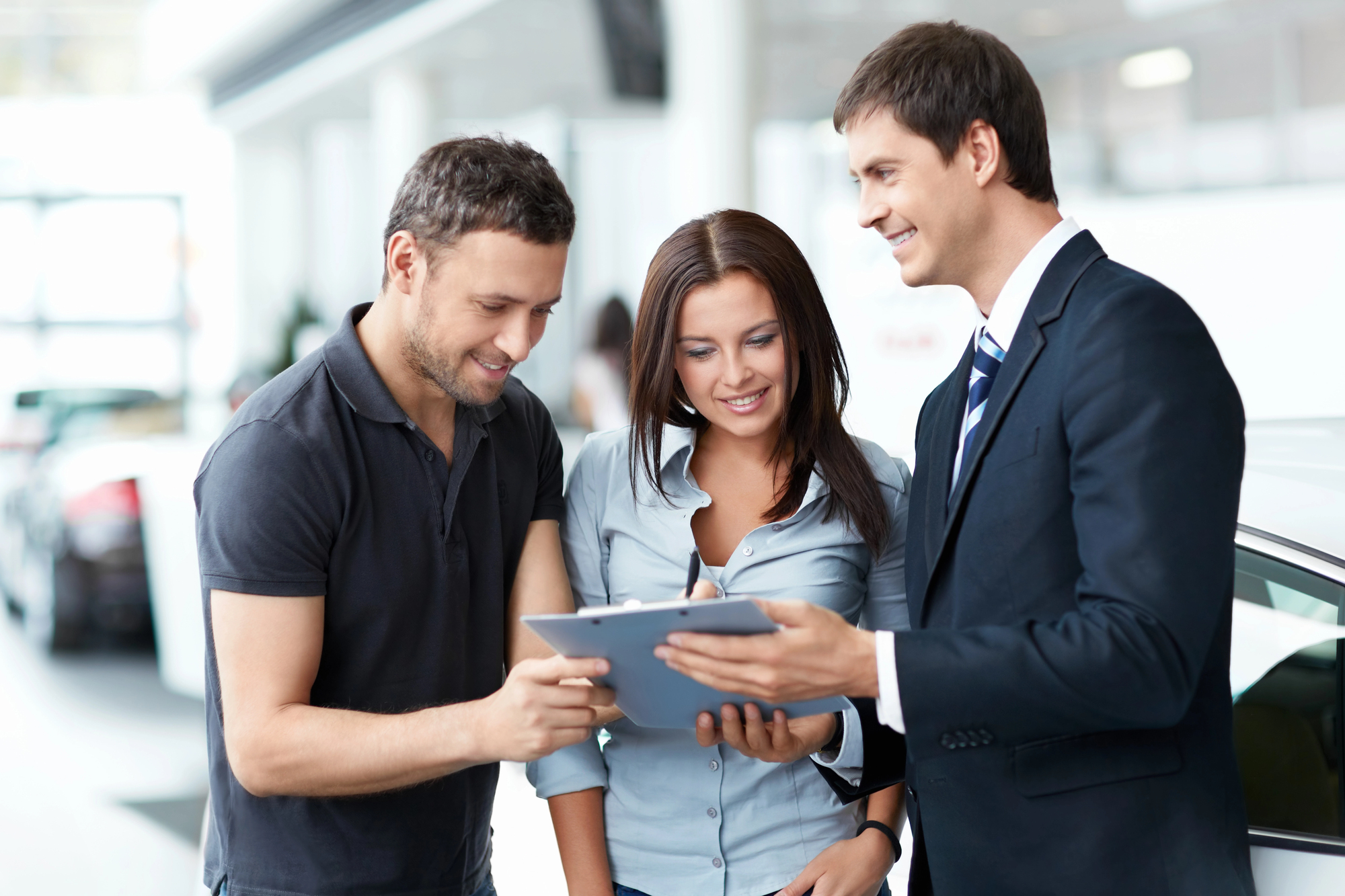 young couple getting a price quote from car salesmen at a dealership